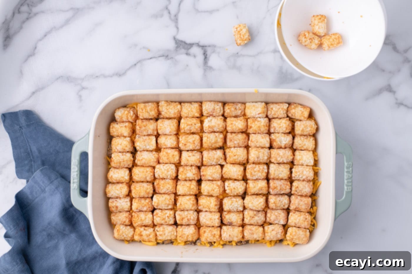 Special Sauce Cheeseburger Casserole 12 tater tots placed neatly on top of ground beef and shredded cheese in casserole