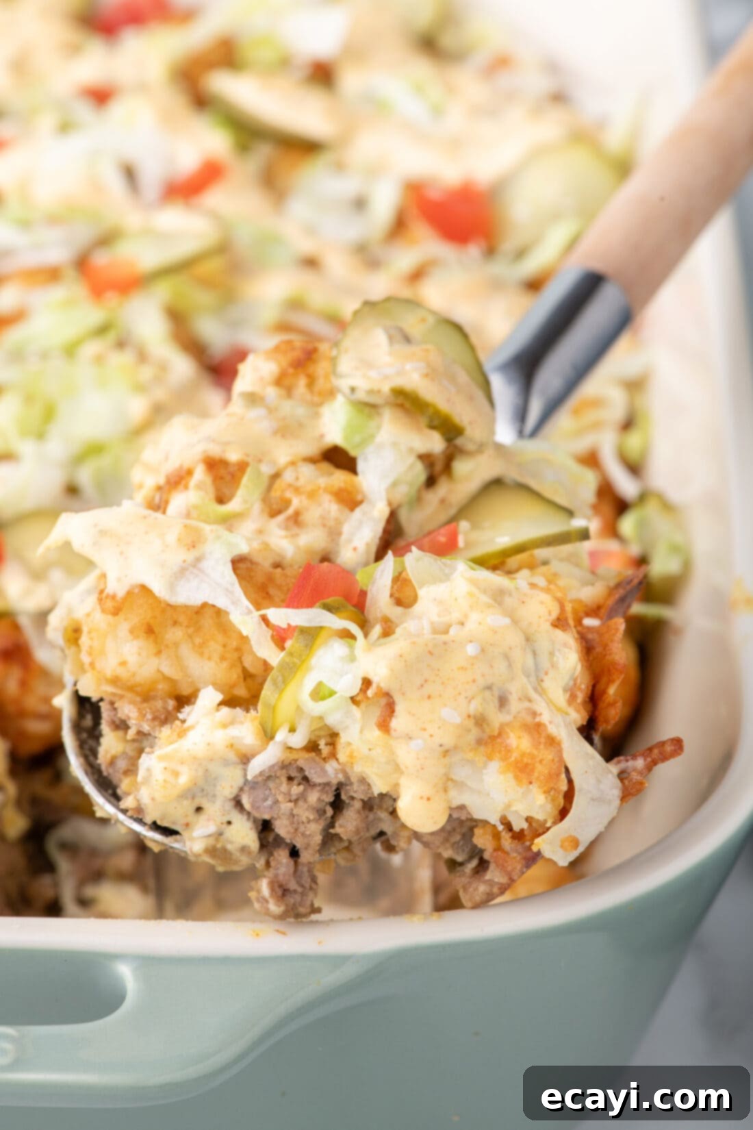 Special Sauce Cheeseburger Casserole 15 Spoonful of Big Mac Casserole being lifted out of a casserole dish, showing layers and toppings