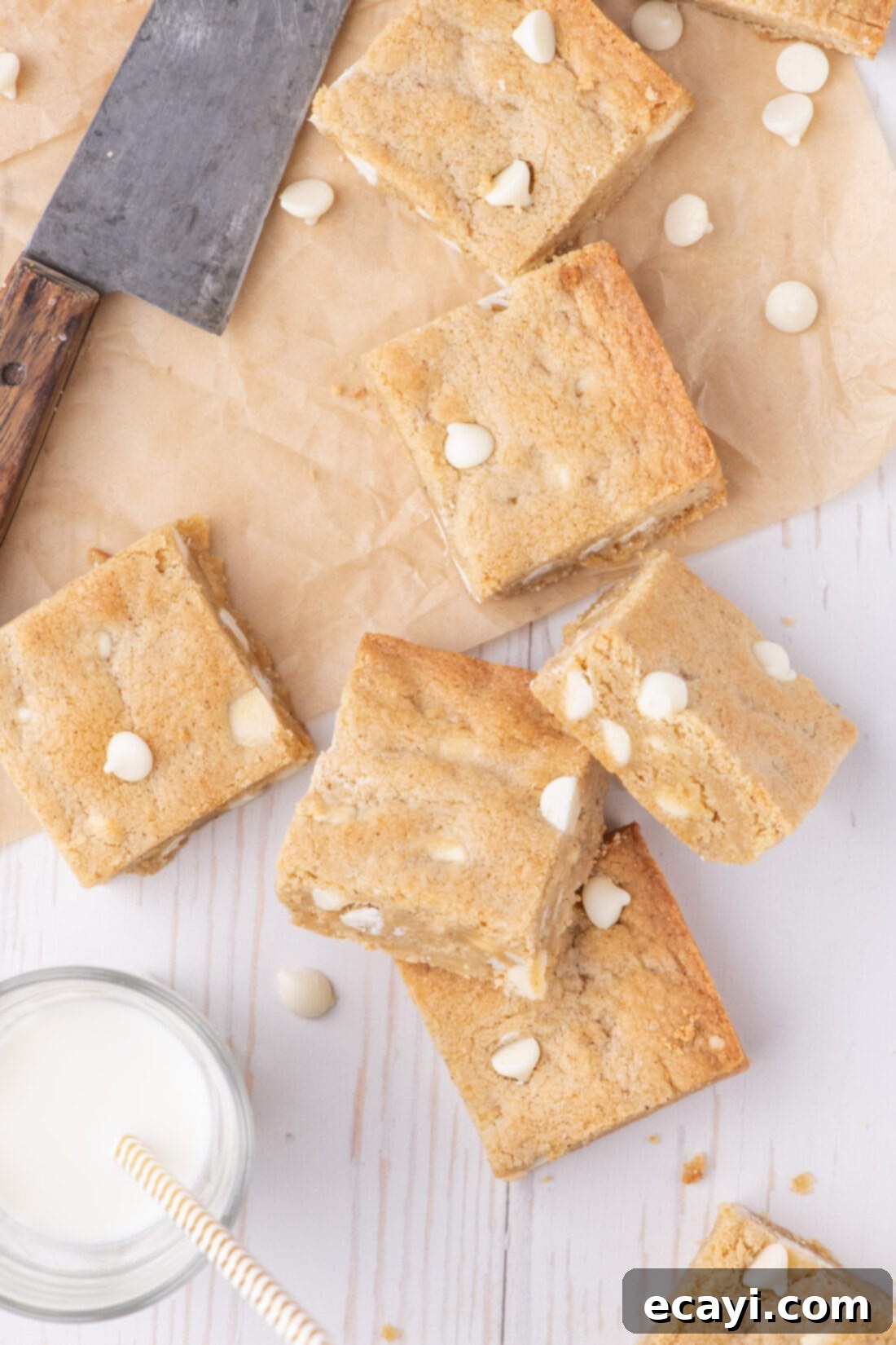 Chewy Blondie Bars 3 Blondies resting on parchment paper with a glass of milk