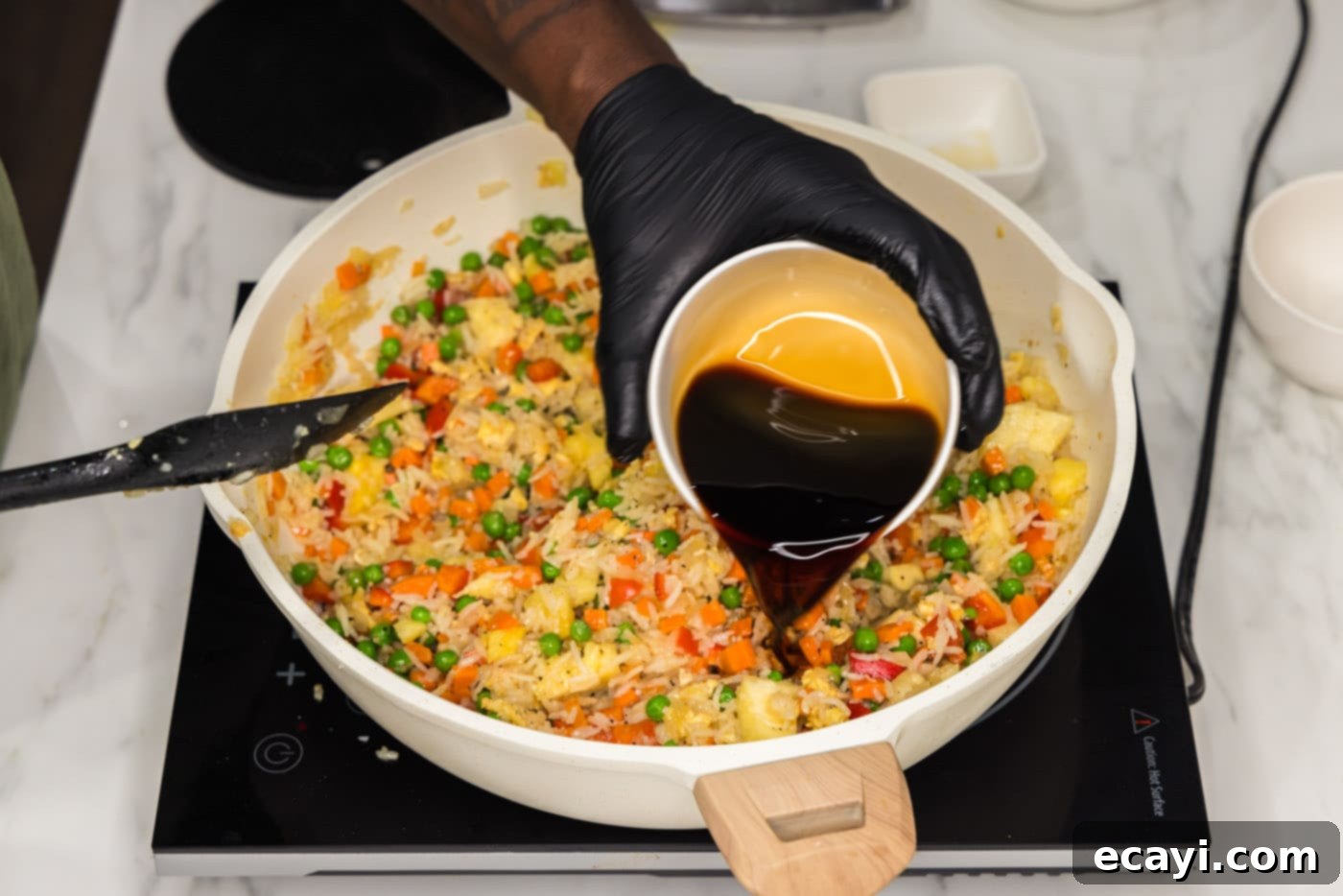 Sun-Kissed Pineapple Rice 13 Low sodium soy sauce being poured generously into the skillet of pineapple fried rice, adding the final layer of savory depth.