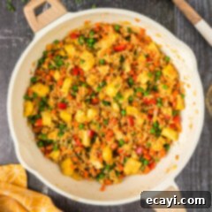 Sun-Kissed Pineapple Rice 16 Overhead photo of Pineapple Fried Rice in a skillet with a spoon, highlighting the golden rice, colorful vegetables, and scrambled eggs.