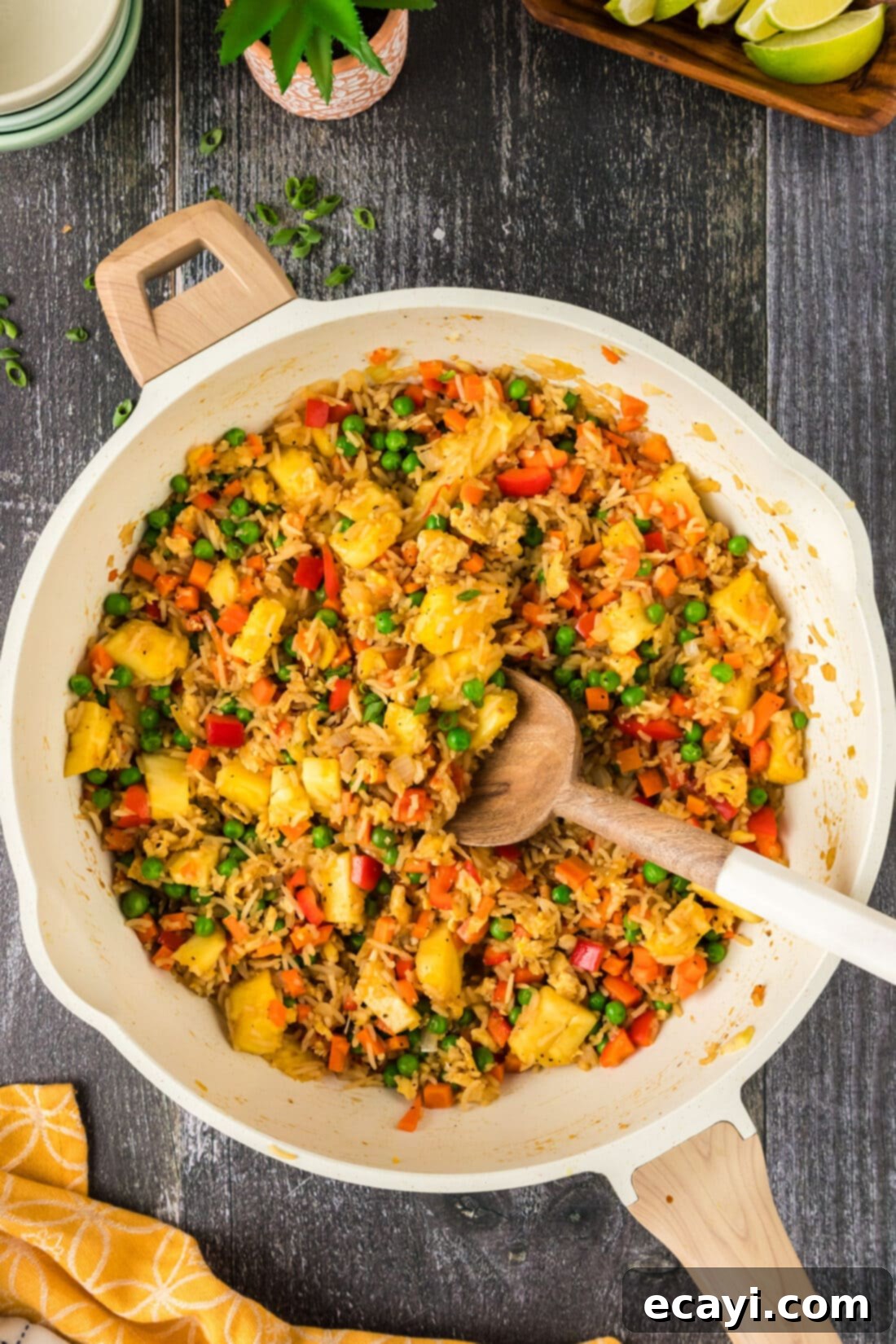 Sun-Kissed Pineapple Rice 3 Pineapple Fried Rice being stirred in a large skillet, highlighting the golden rice, colorful vegetables, and scrambled eggs, ready to be served.