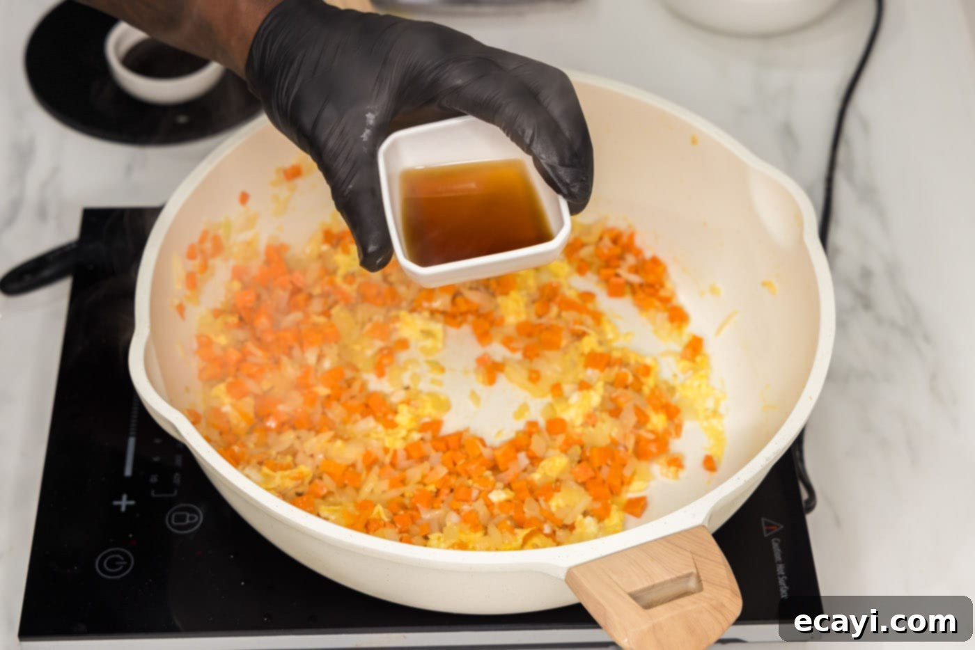 Sun-Kissed Pineapple Rice 8 Fish sauce being poured into the skillet with the scrambled eggs and vegetables, adding a crucial layer of umami flavor to the fried rice.