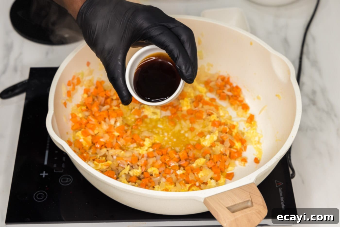 Sun-Kissed Pineapple Rice 9 Oyster sauce being added to the skillet containing the egg and vegetables, enriching the dish with its savory-sweet glaze.