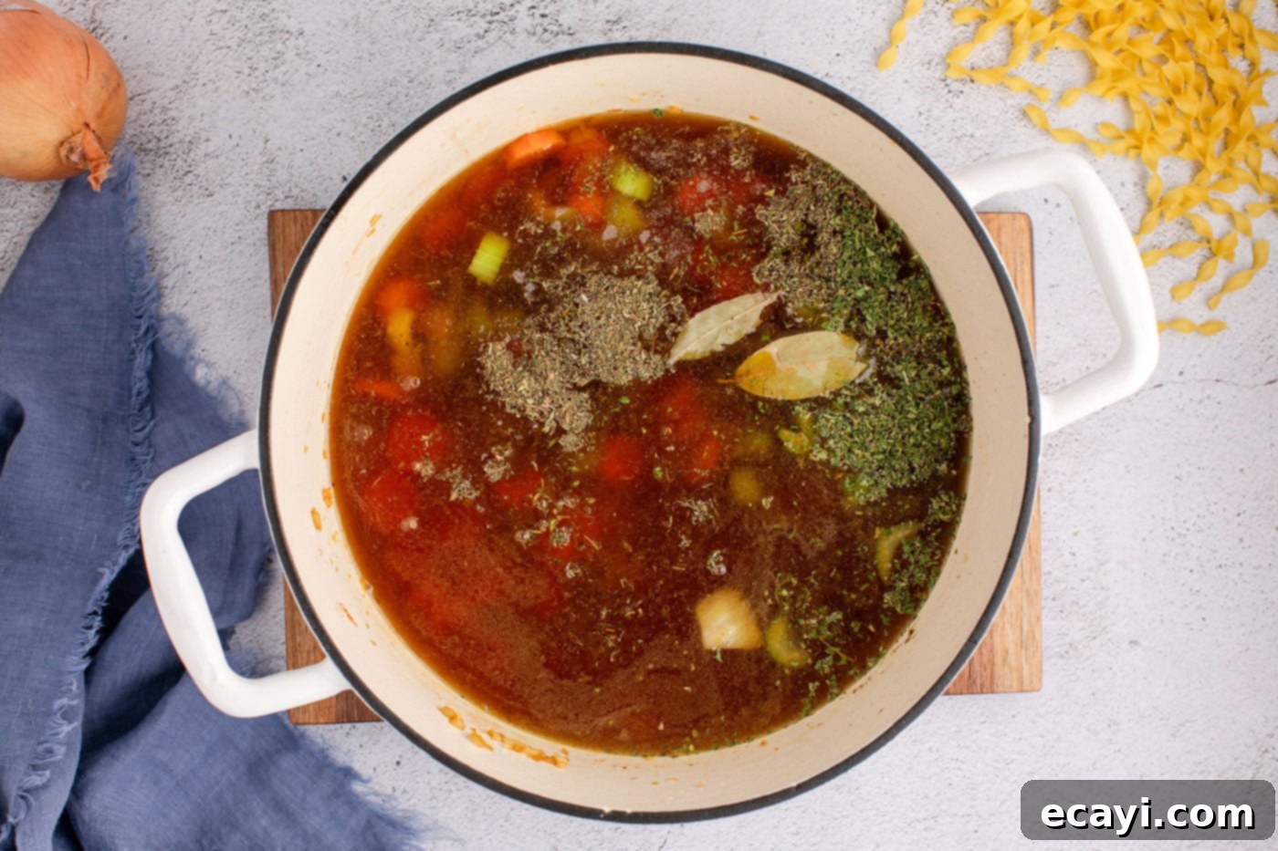Hearty Beef Noodle Bowl 8 Beef broth and various seasonings being added to the sautéed vegetable mix in a Dutch oven for beef noodle soup.