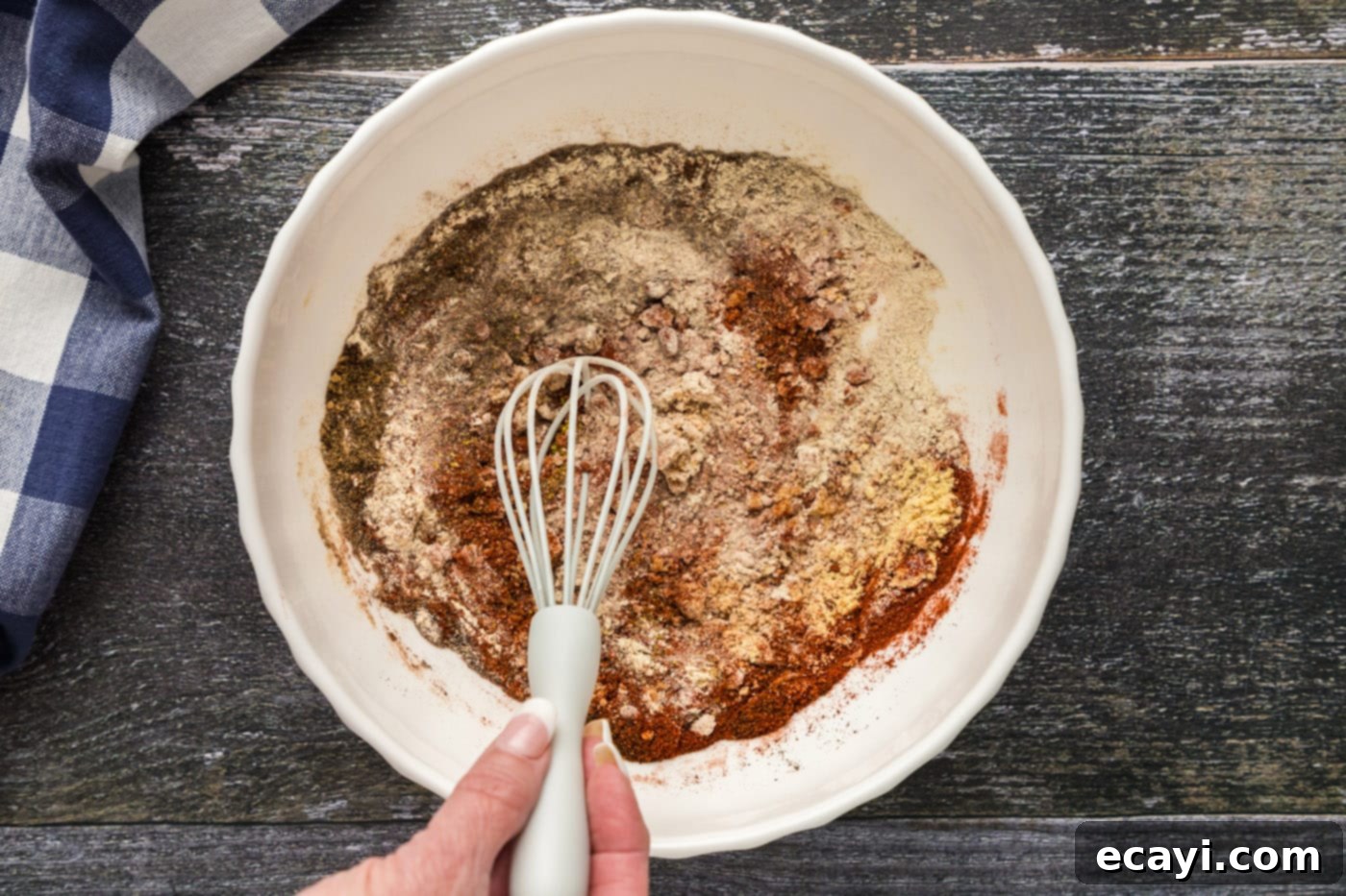 Signature Pulled Pork Blend 5 All the ingredients for pulled pork dry rub being whisked together in a white bowl.