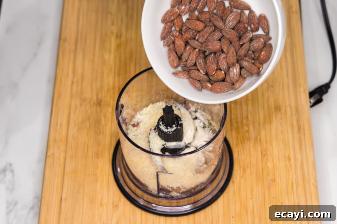 Golden Almond Chicken 5 pouring almonds into food processor with seasonings and parmesan cheese