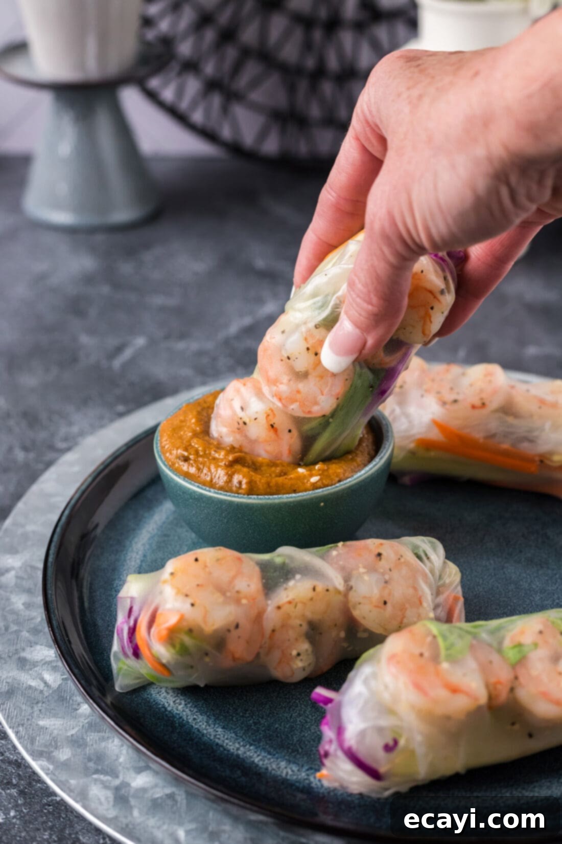 Hand-Rolled Shrimp Delights 3 Shrimp Spring Roll being dipped into a a bowl of peanut sauce