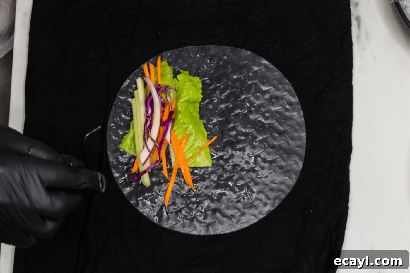 Hand-Rolled Shrimp Delights 8 carrots, lettuce, and cabbage added to spring roll wrapper on a damp towel