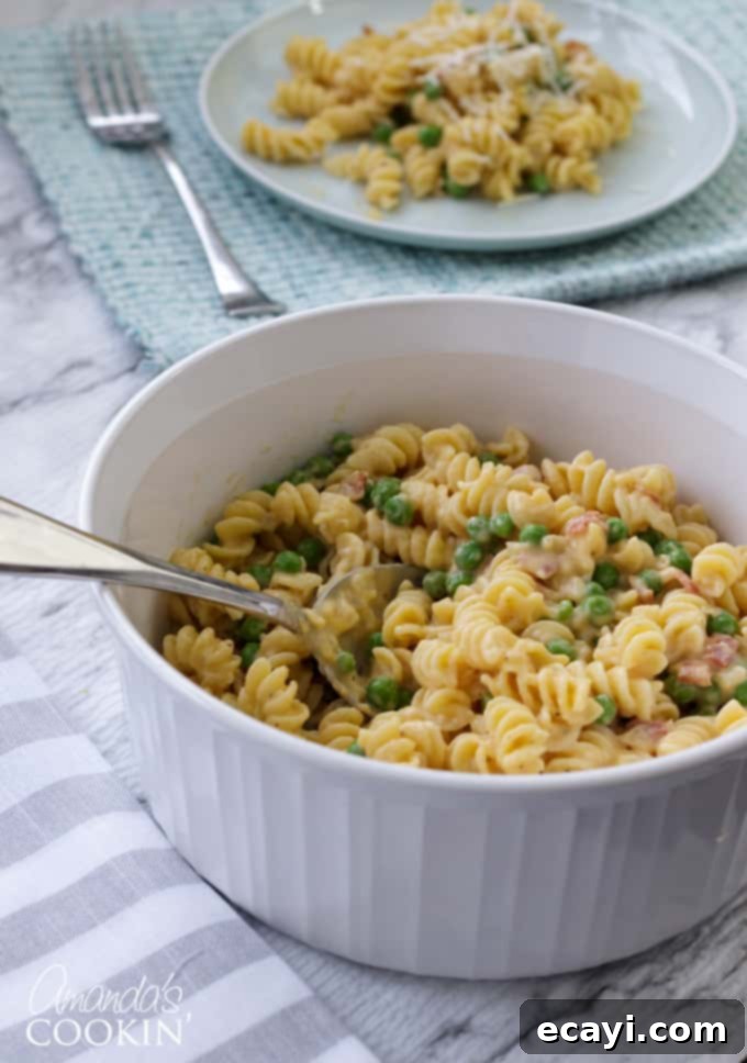 Bacon and peas combined with sharp cheddar make a delicious meal in this easy Rotini Peas and Cheese. It's mac and cheese for grown ups! #macandcheese #macaroniandcheese #rotinipasta #rotinirecipes #pastarecipes #pastaandcheese #cheddarcheese #peas #bacon #sidedish #stovetop  bowl of rotini with peas and cheese