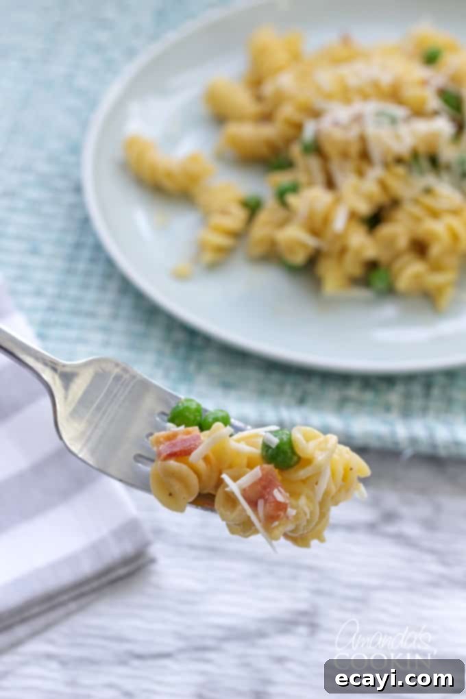 Bacon and peas combined with sharp cheddar make a delicious meal in this easy Rotini Peas and Cheese. It's mac and cheese for grown ups! #macandcheese #macaroniandcheese #rotinipasta #rotinirecipes #pastarecipes #pastaandcheese #cheddarcheese #peas #bacon #sidedish #stovetop  forkful of rotini peas and cheese