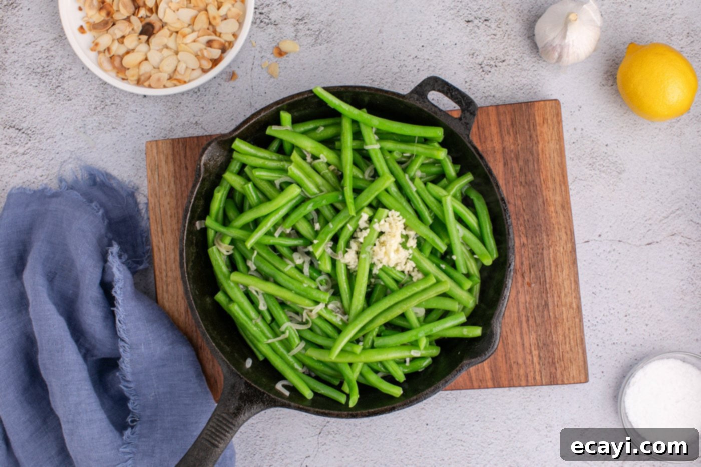 Almond-Kissed Crisp Green Beans 11 Skillet of green beans with garlic and lemon juice added, being tossed to combine flavors before serving.
