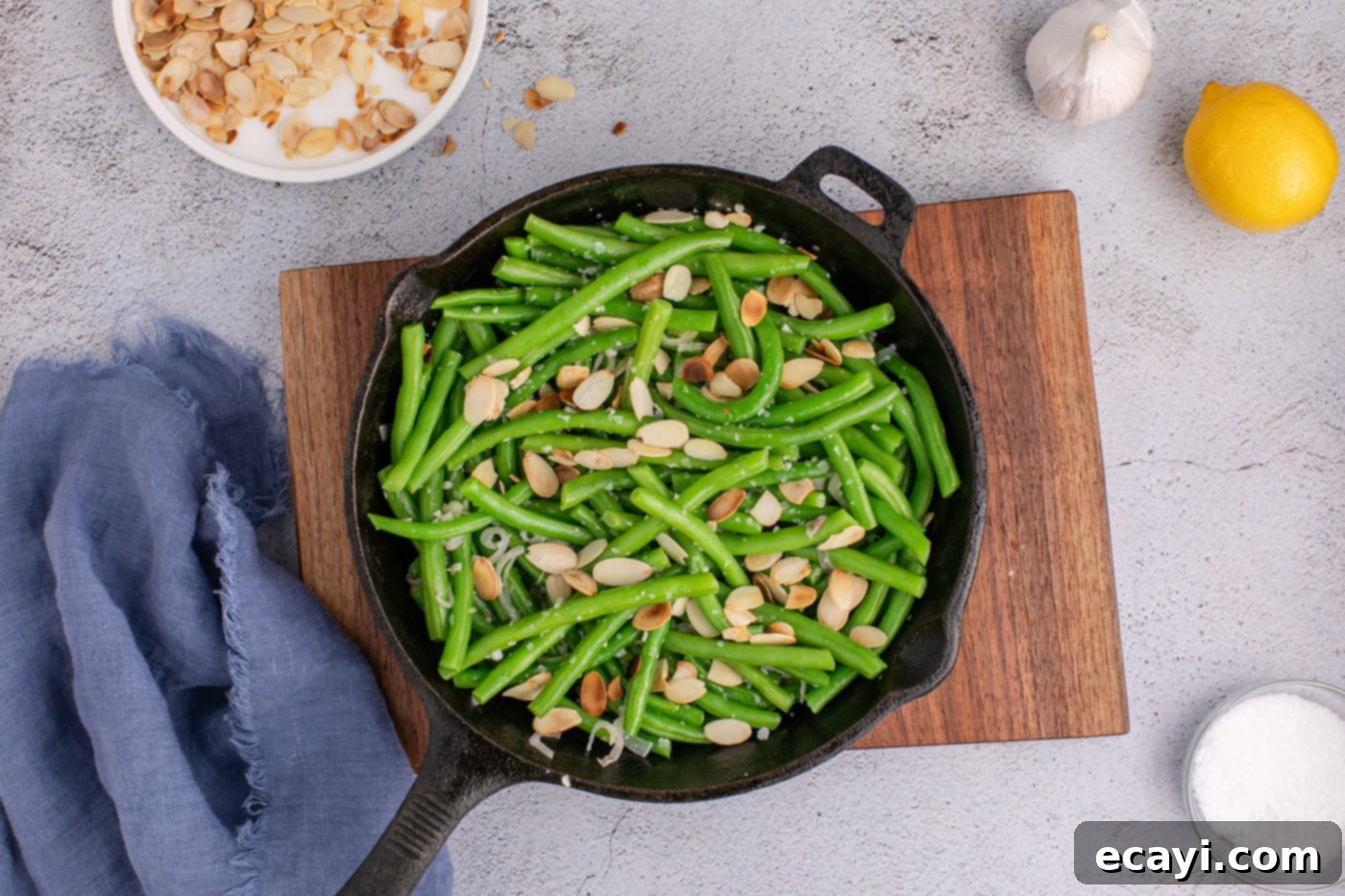 Almond-Kissed Crisp Green Beans 12 Toasted sliced almonds being added to the green beans in the skillet, ready for a final toss and serving.