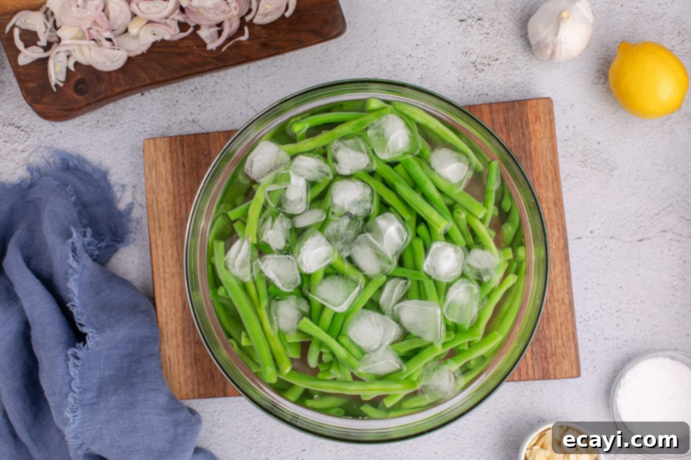 Almond-Kissed Crisp Green Beans 6 Transferring blanched green beans from boiling water to an ice bath, demonstrating how to stop the cooking process for crisp beans.
