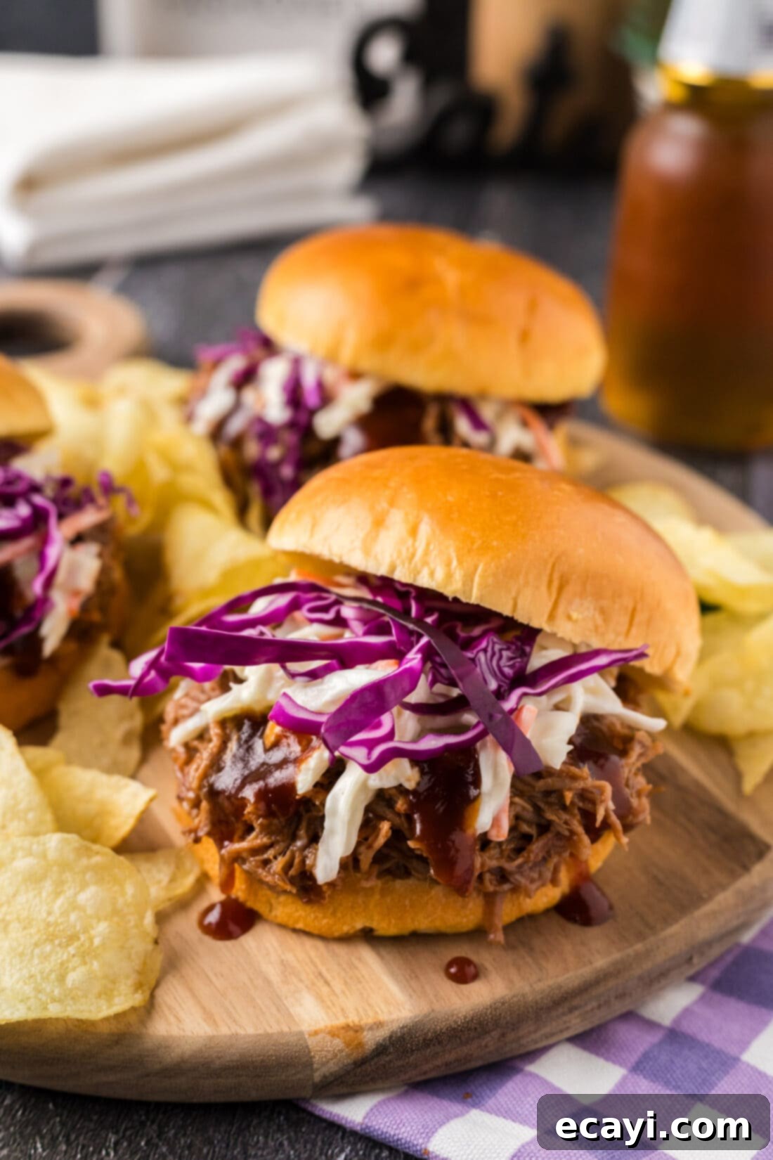 Smoky BBQ Pulled Pork Sandwiches 3 Pulled Pork Sandwich on a wooden board with the top bun sliding off