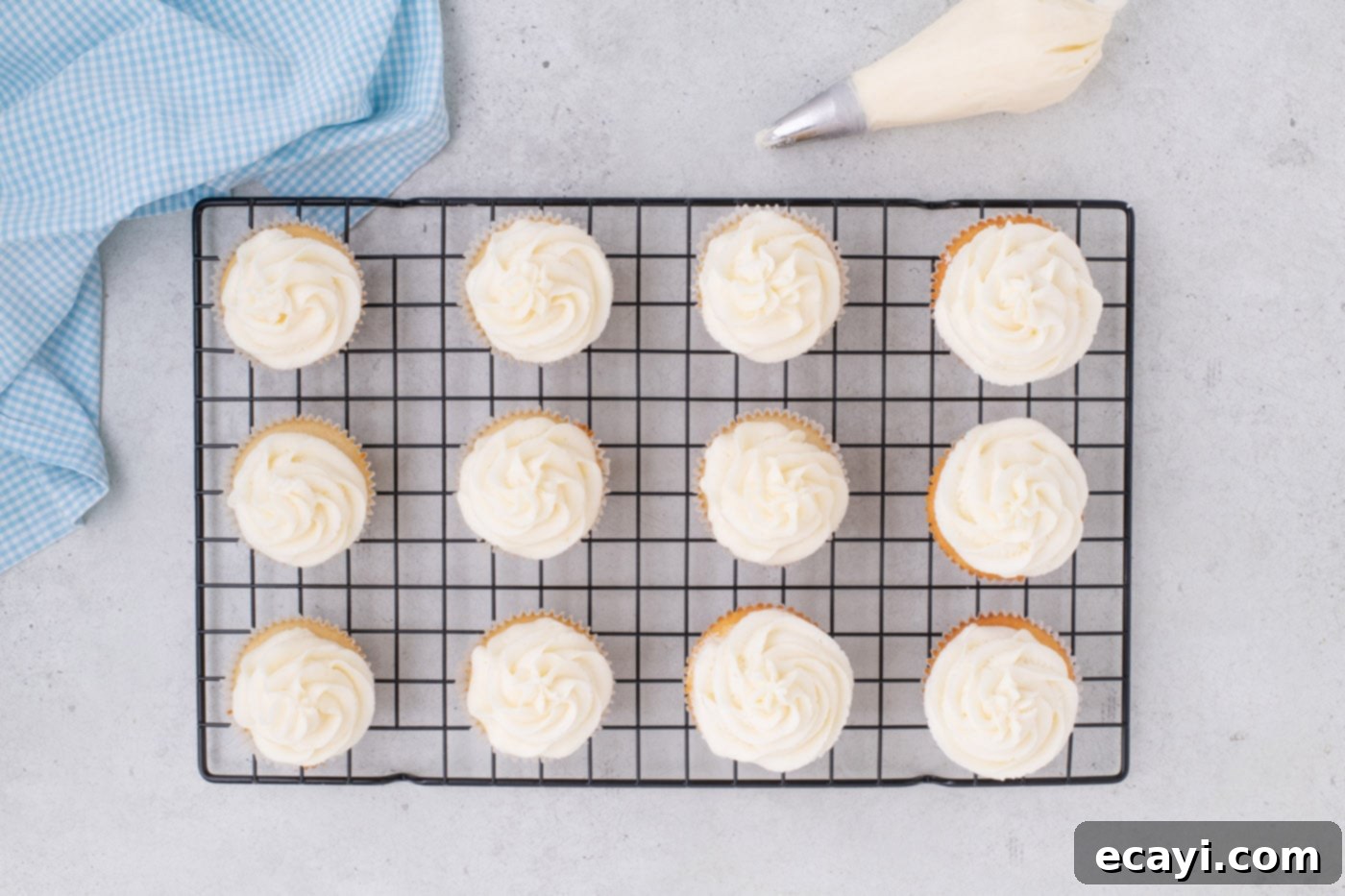 Vanilla Cupcakes 12 Delightful frosted vanilla cupcakes arranged on a wire cooling rack