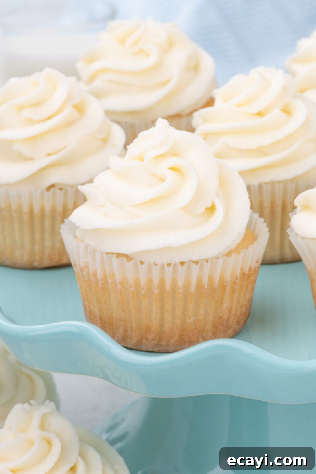 Vanilla Cupcakes 13 Elegantly frosted vanilla cupcakes displayed on a chic blue cake stand