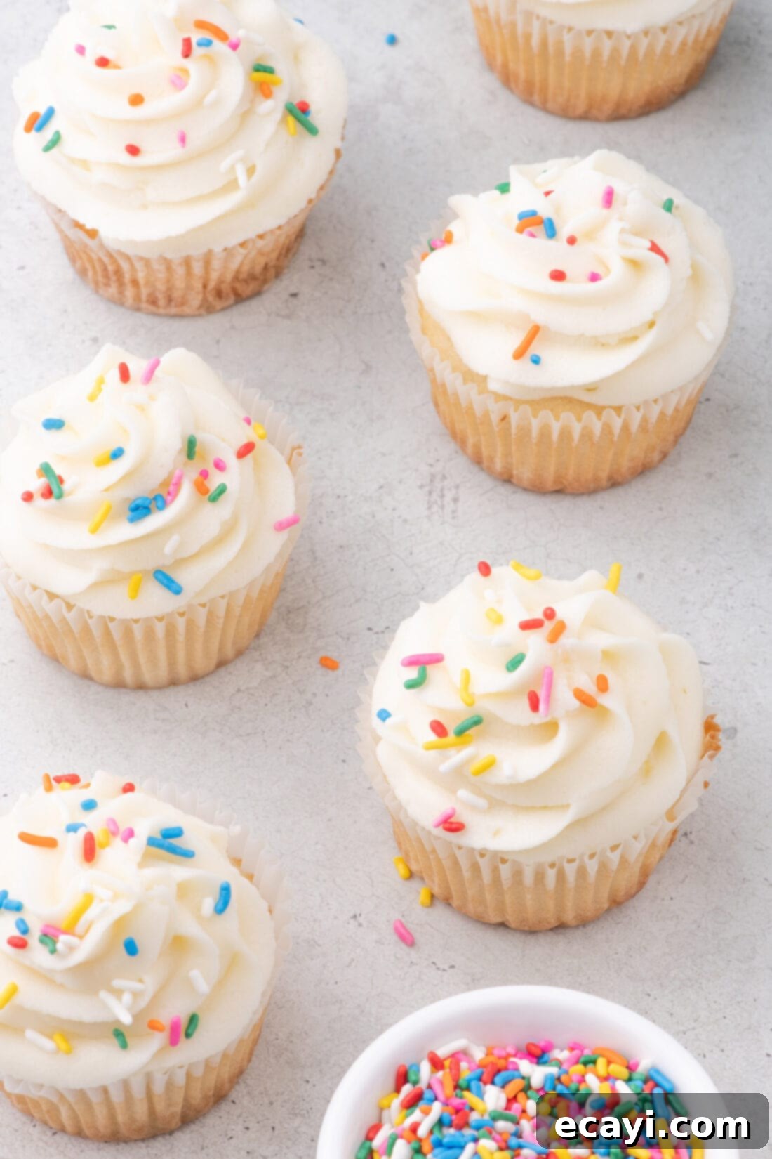 Vanilla Cupcakes 3 Delightful vanilla cupcakes adorned with colorful rainbow sprinkles