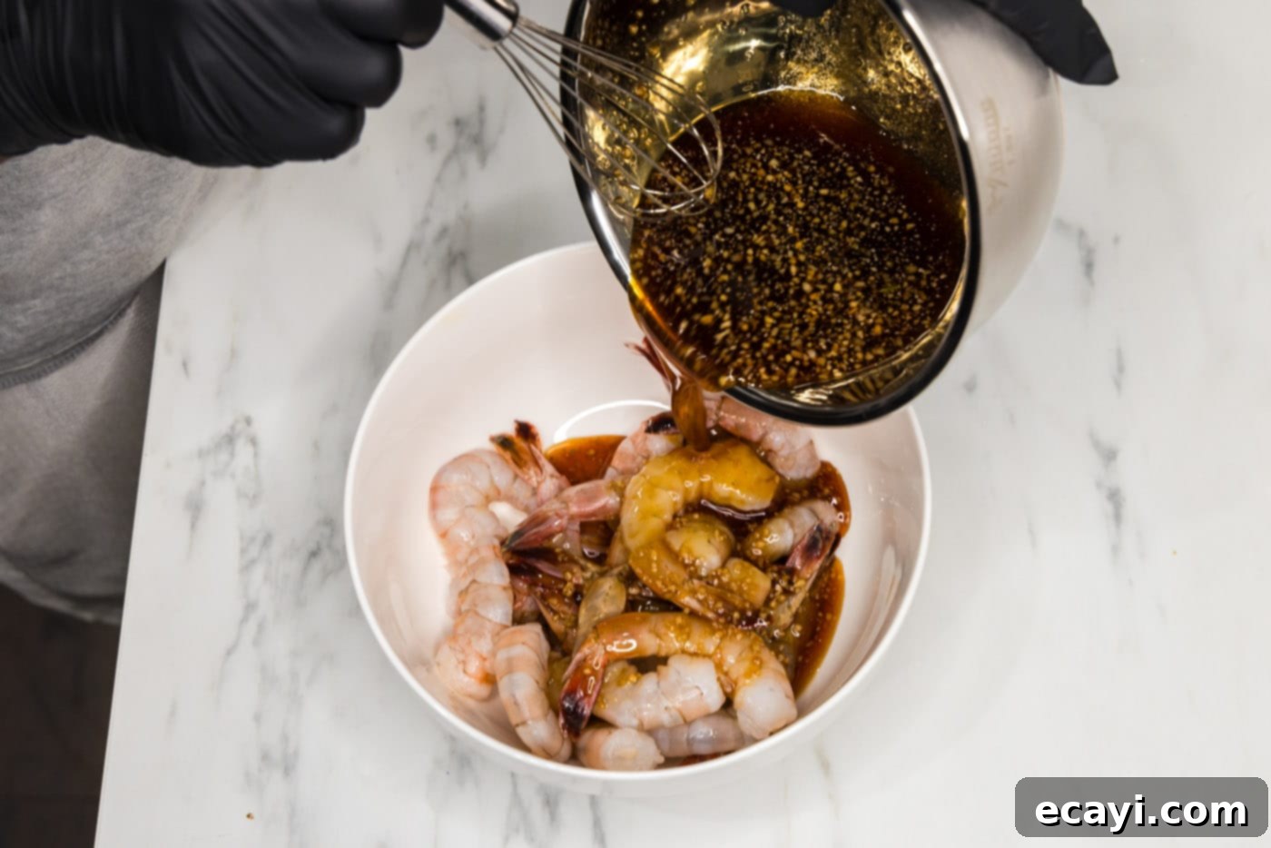 Glazed Honey Garlic Shrimp 6 pouring the rich honey garlic sauce over the raw shrimp in a bowl