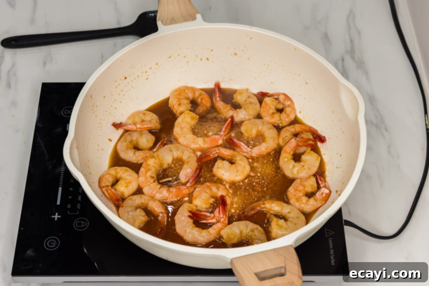 Glazed Honey Garlic Shrimp 8 cooked shrimp simmering in a sticky honey garlic sauce in a large skillet
