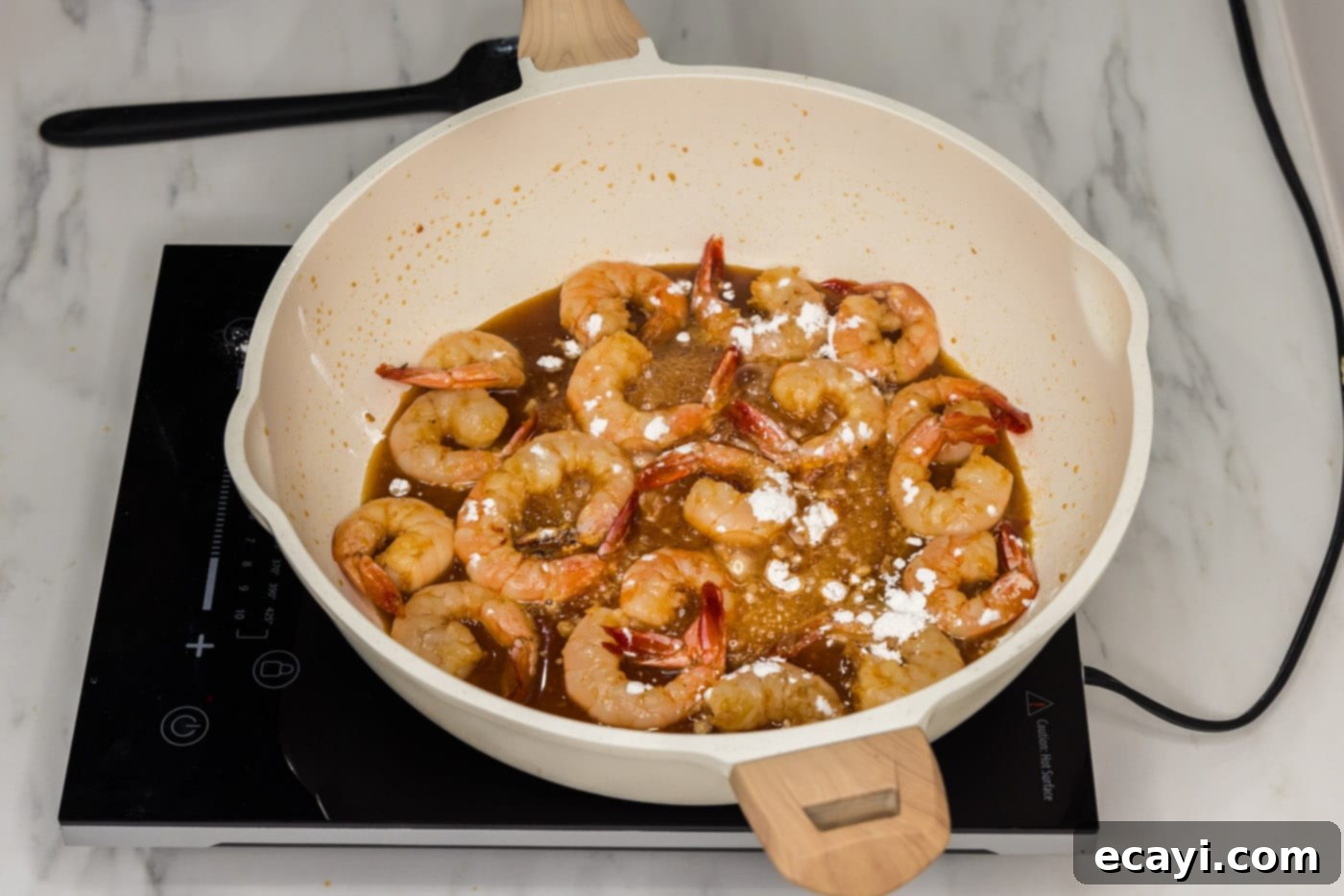 Glazed Honey Garlic Shrimp 9 cornstarch being sprinkled over honey garlic shrimp in a skillet to thicken the sauce