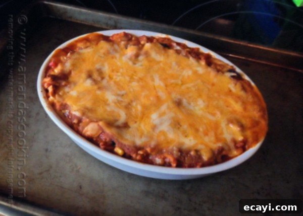 Golden Chicken Tostada Bake 8 The baked chicken tostada casserole, golden and bubbly from the oven, with melted cheese and a hint of the delicious layers beneath, ready for garnishing.