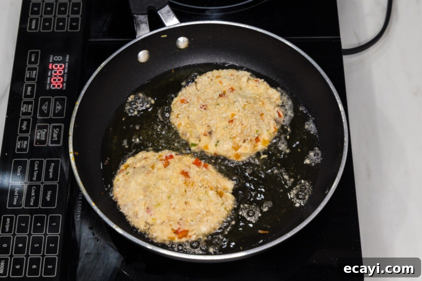 Crispy Fish Sandwich 12 frying fish cakes in a skillet of hot oil, creating a golden crust