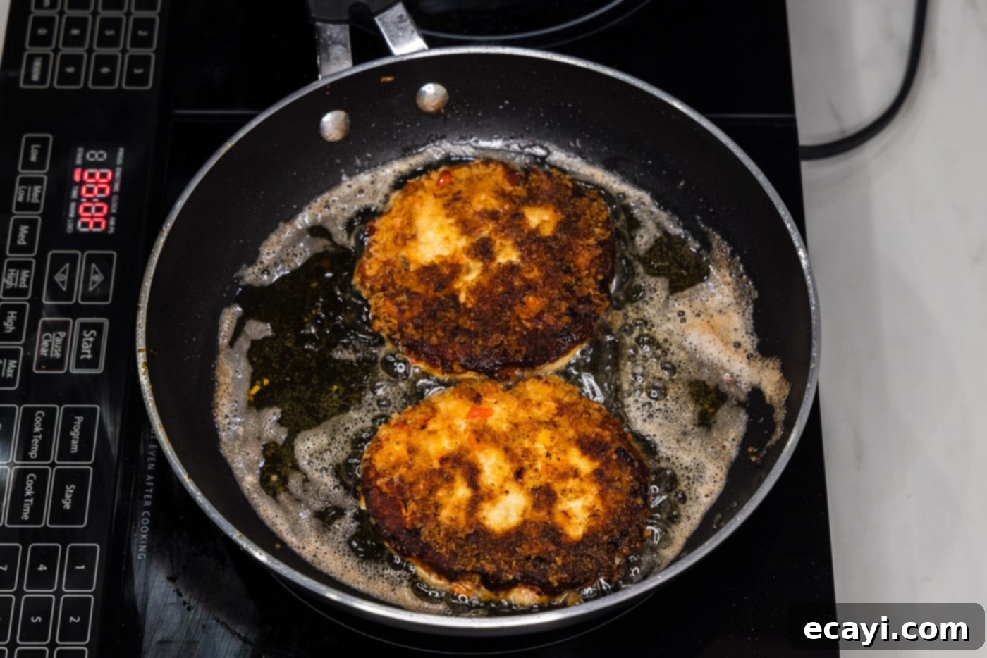Crispy Fish Sandwich 13 freshly fried golden-brown fish burgers in a skillet, ready to be removed