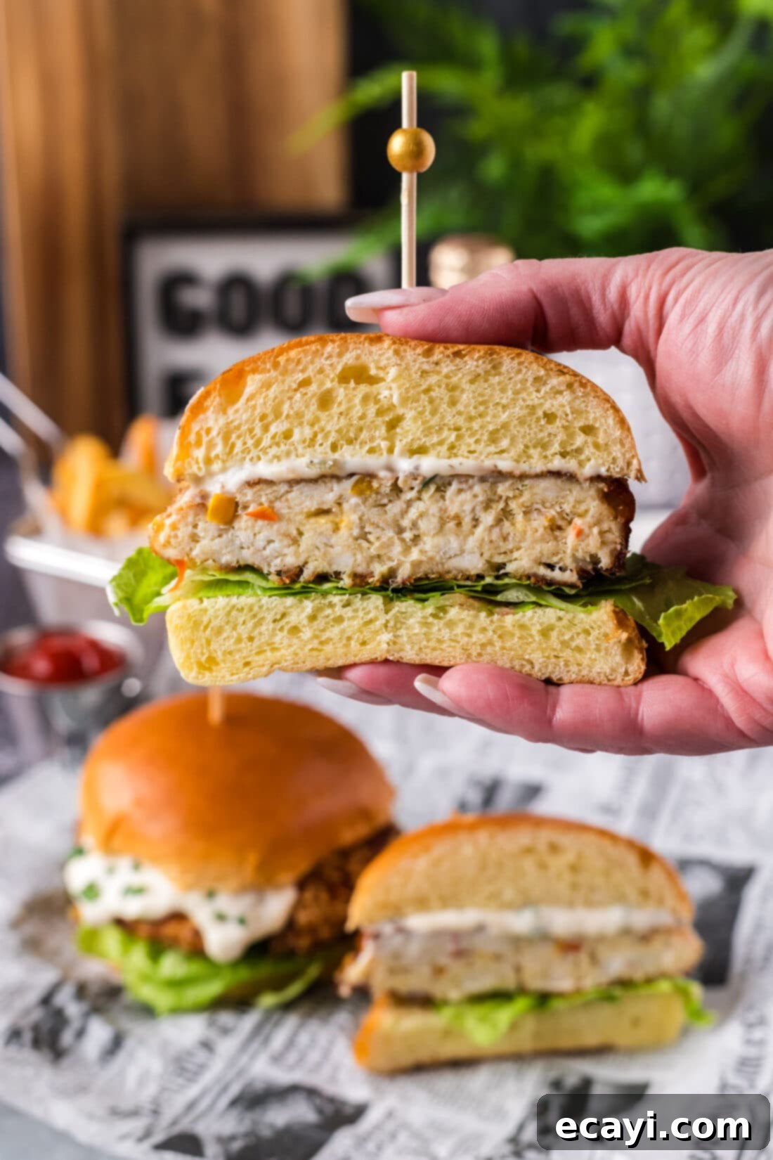 Crispy Fish Sandwich 3 Hand holding up a Fish Burger cut in half, showing crispy exterior and flaky interior