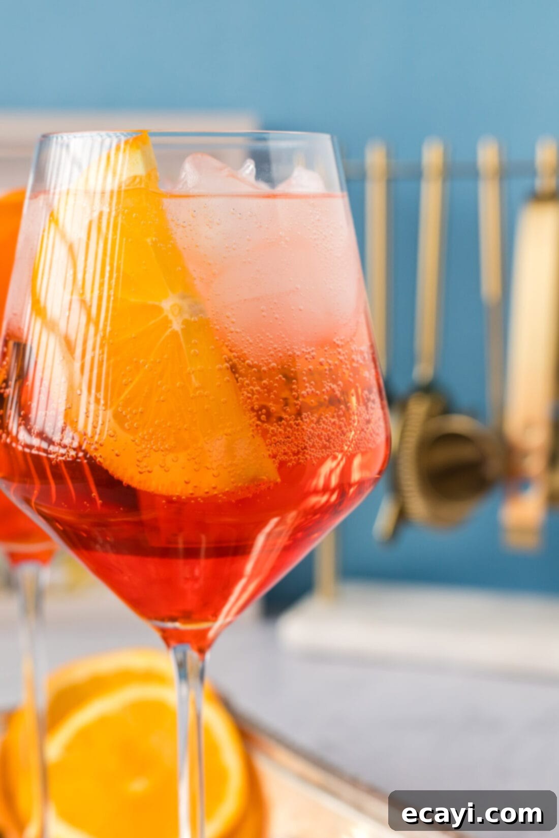 Golden Hour Aperol Spritz 2 Close up photo of a vibrant Aperol Spritz cocktail, garnished with an orange slice and brimming with ice.