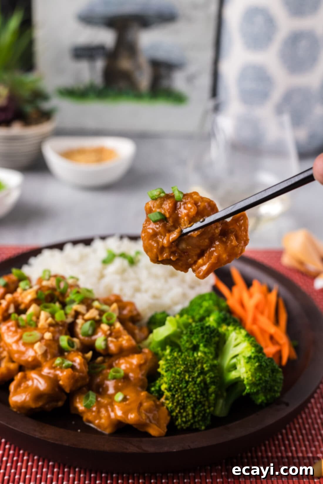 Creamy Peanut Butter Chicken 2 Chopsticks holding up a piece of Peanut Butter Chicken, showcasing its golden crispy coating and rich sauce