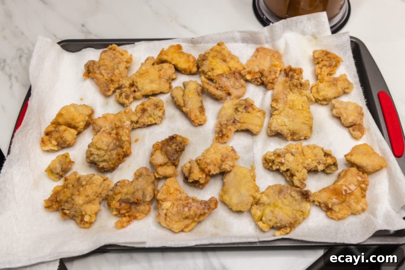Creamy Peanut Butter Chicken 11 crispy coated chicken pieces resting on a paper towel-lined plate to drain oil
