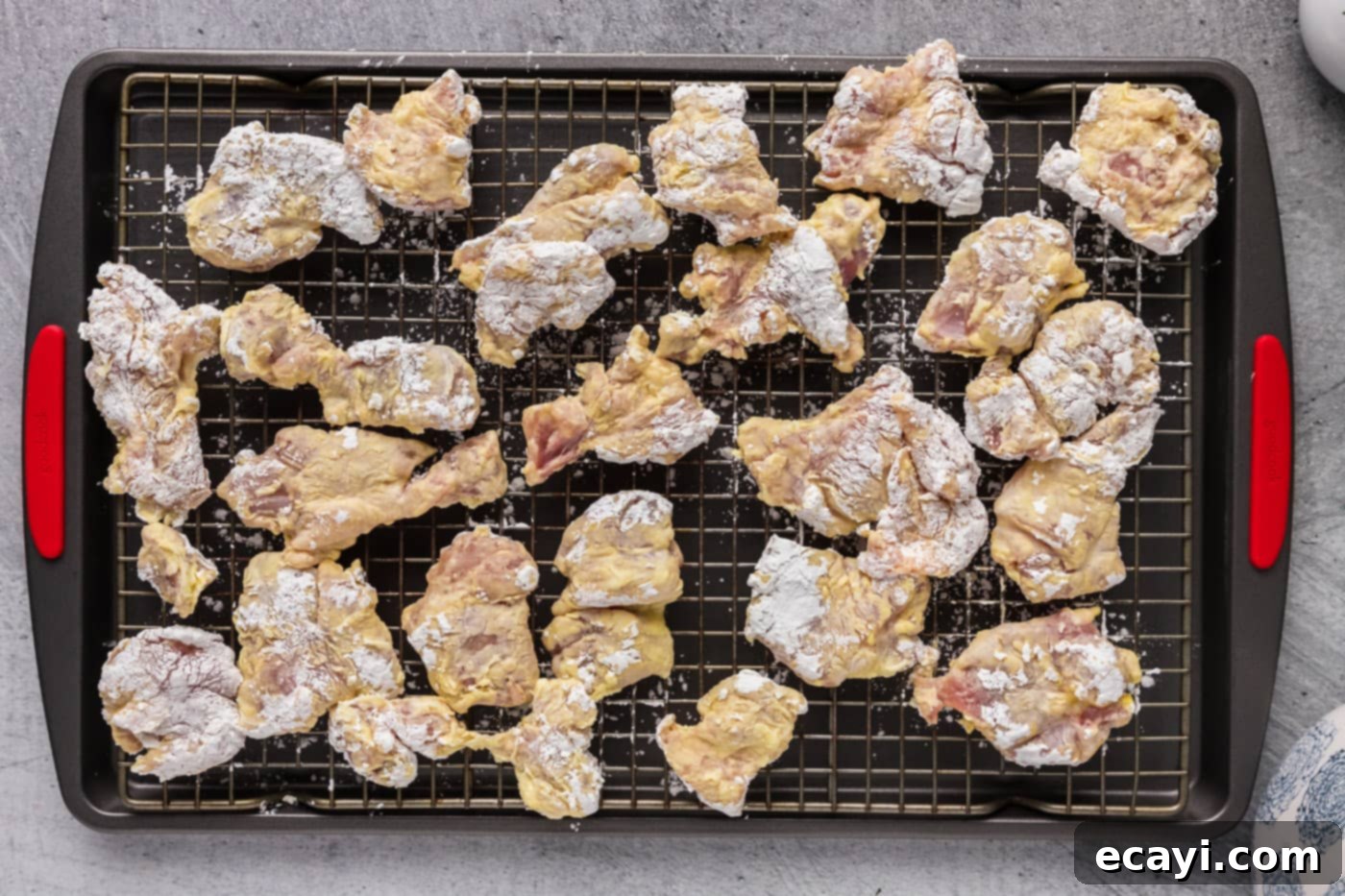 Creamy Peanut Butter Chicken 8 dredged chicken pieces resting on a wire rack, ready for frying