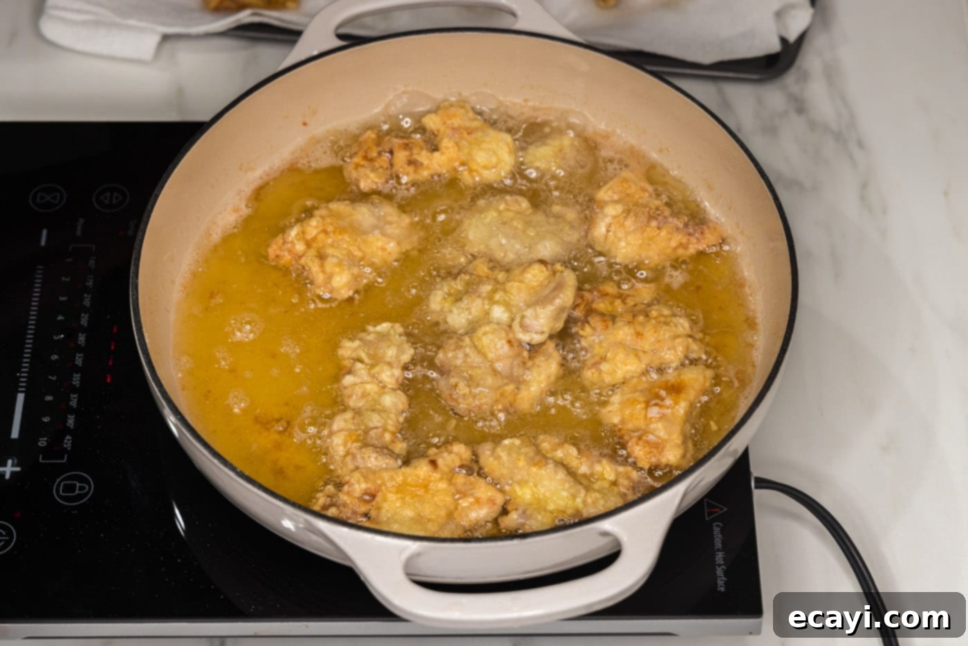 Creamy Peanut Butter Chicken 10 chicken pieces frying in hot oil, bubbling and crisping up
