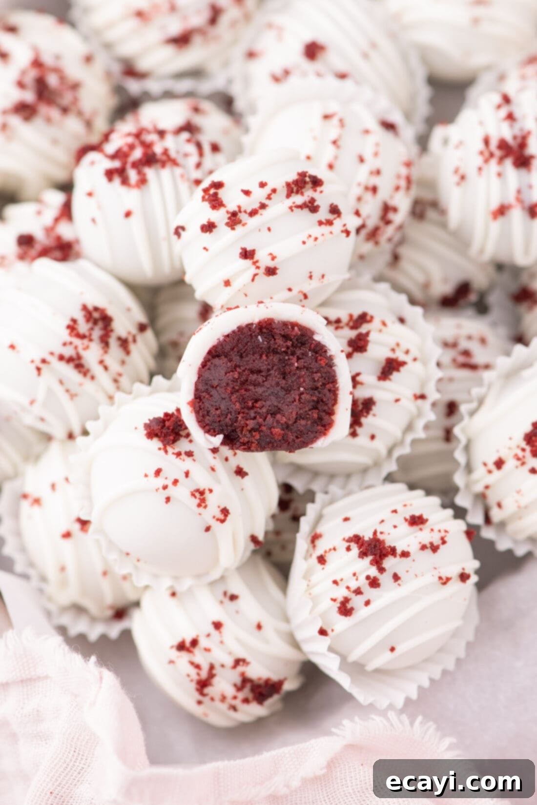 Red Velvet Truffles 2 Two Red Velvet Cake Balls, one whole and one cut in half revealing its moist interior and frosting, resting on a serving plate.