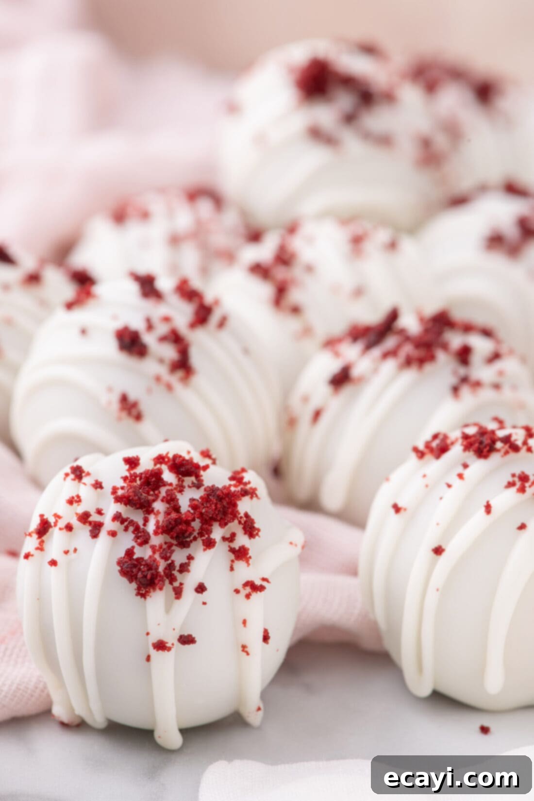 Red Velvet Truffles 3 Close-up photo of several perfectly rounded Red Velvet Cake Balls, coated in white chocolate and sprinkled with red velvet cake crumbs.
