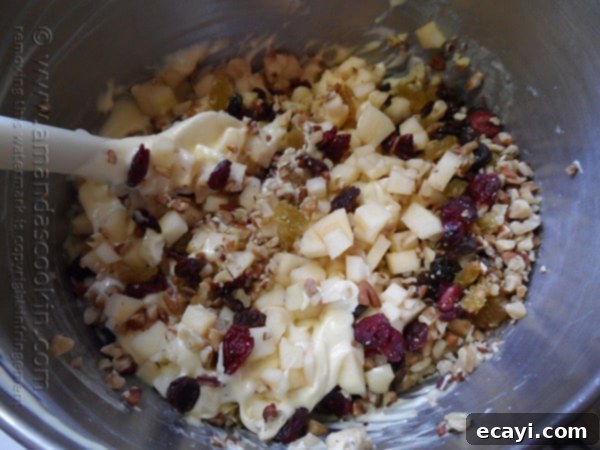 Classic Merryfield Apple Cake 9 A mixing bowl filled with yellow cake batter, generously folded with the chopped apples, nuts, and dried fruits, creating a rich, textured mixture.