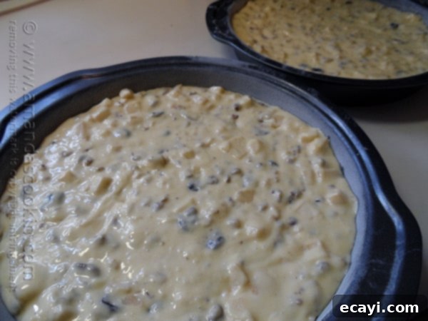Classic Merryfield Apple Cake 10 Two round cake pans, each filled evenly with the lumpy, fruit and nut-laden apple cake batter, ready for baking.