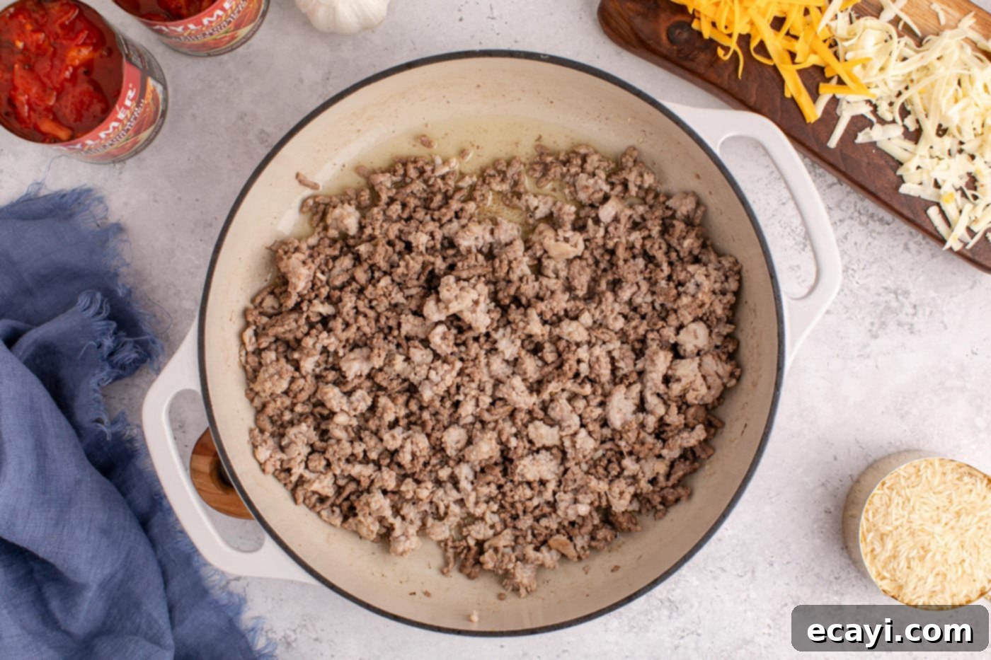 Deconstructed Stuffed Pepper Bake 5 Ground beef and Italian sausage browning in a skillet with a wooden spoon.