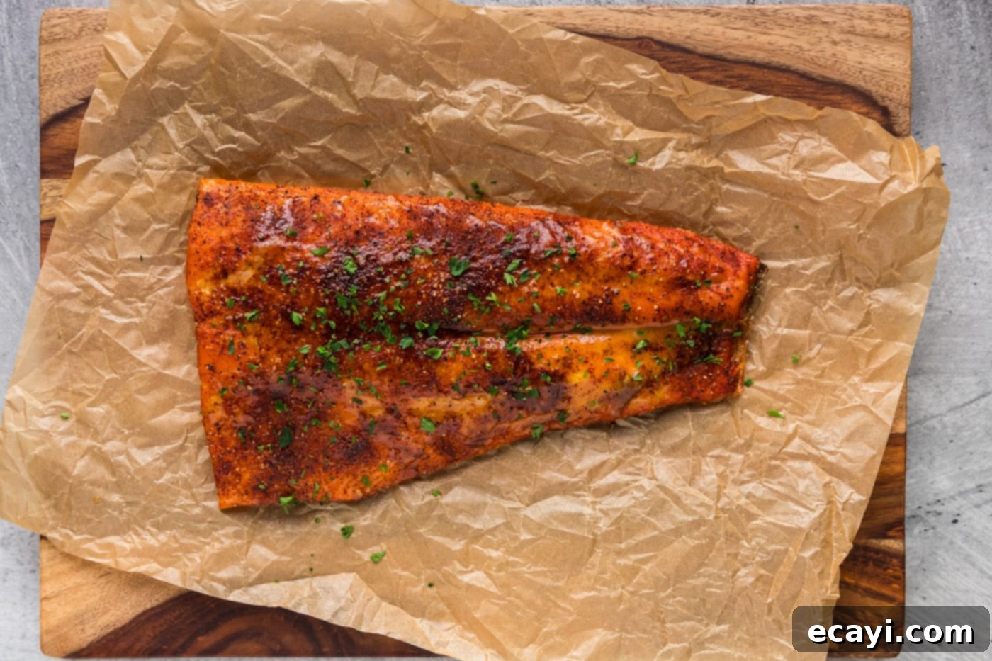 Artisan Smoked Salmon 9 A perfectly smoked salmon fillet, showcasing its beautiful crust, resting on parchment paper on a wooden cutting board, ready to be served.