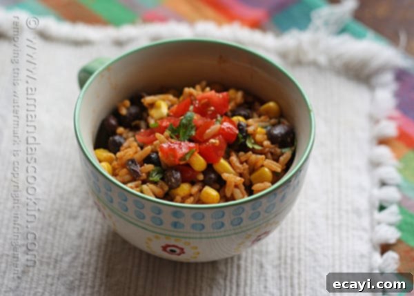 Fiesta Rice with Black Beans and Corn 6 A close up photo of Spanish rice with black beans and corn in a teal and white bowl.