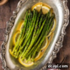 Perfectly Steamed Asparagus 10 Steamed Asparagus resting on lemon slices on a platter, garnished with fresh herbs