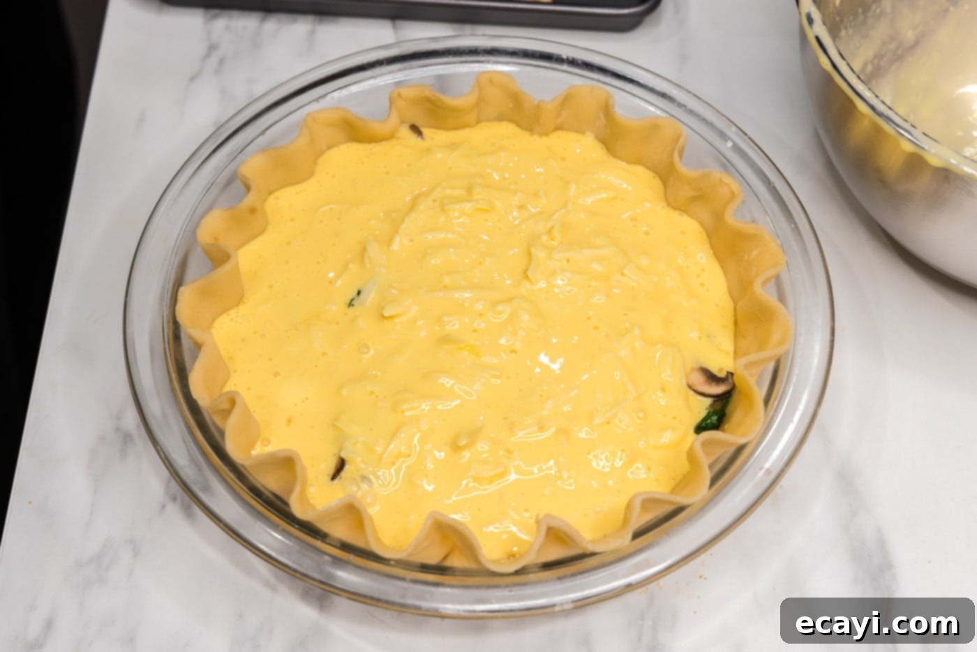 Savory Spinach Mushroom Quiche 12 Egg custard filling being poured over the first layer of spinach and mushrooms in the pie crust.