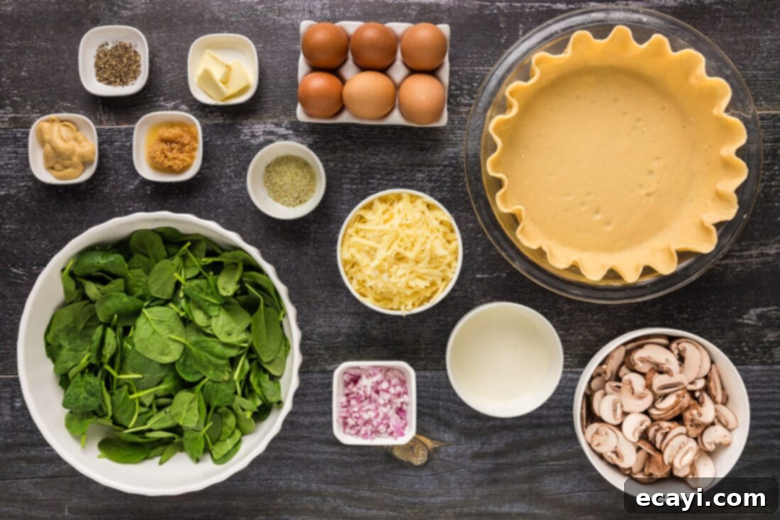Savory Spinach Mushroom Quiche 4 All fresh ingredients for Spinach Mushroom Quiche laid out on a white surface, including eggs, mushrooms, spinach, onion, and cheese.