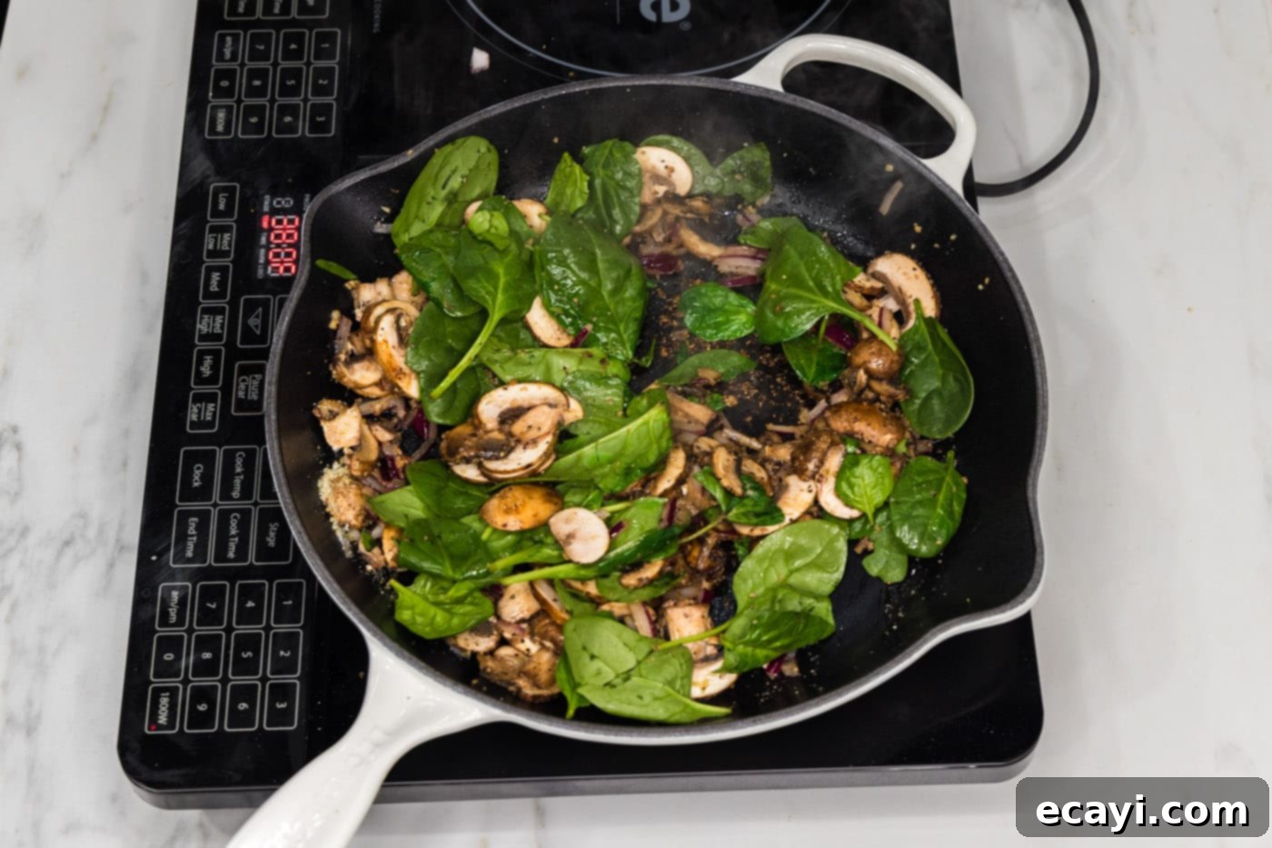 Savory Spinach Mushroom Quiche 7 Fresh spinach leaves being added in batches to the skillet with cooked mushrooms and onion.