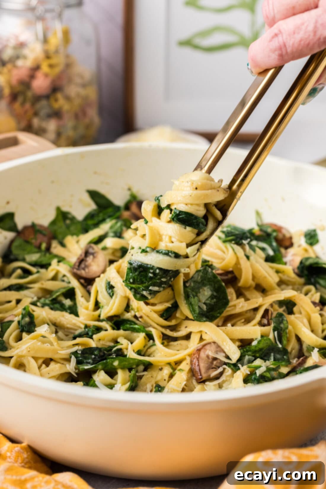 Vibrant Spinach Fettuccine 2 Spinach Fettuccine being lifted from a skillet with tongs, showcasing its creamy texture and fresh ingredients