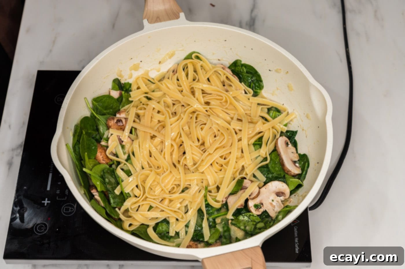 Vibrant Spinach Fettuccine 11 Cooked fettuccine noodles being mixed with the spinach and mushroom mixture in a large skillet