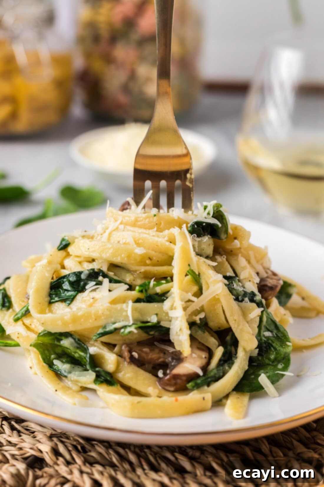 Vibrant Spinach Fettuccine 12 Close-up of a fork stuck inside a heaping portion of creamy Spinach Fettuccine on a plate, highlighting its appetizing texture