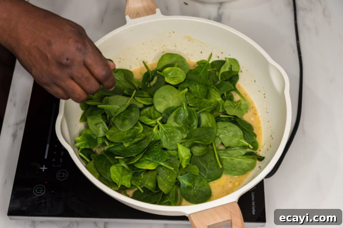 Vibrant Spinach Fettuccine 9 Fresh spinach leaves wilting rapidly in a skillet over the prepared creamy pasta sauce