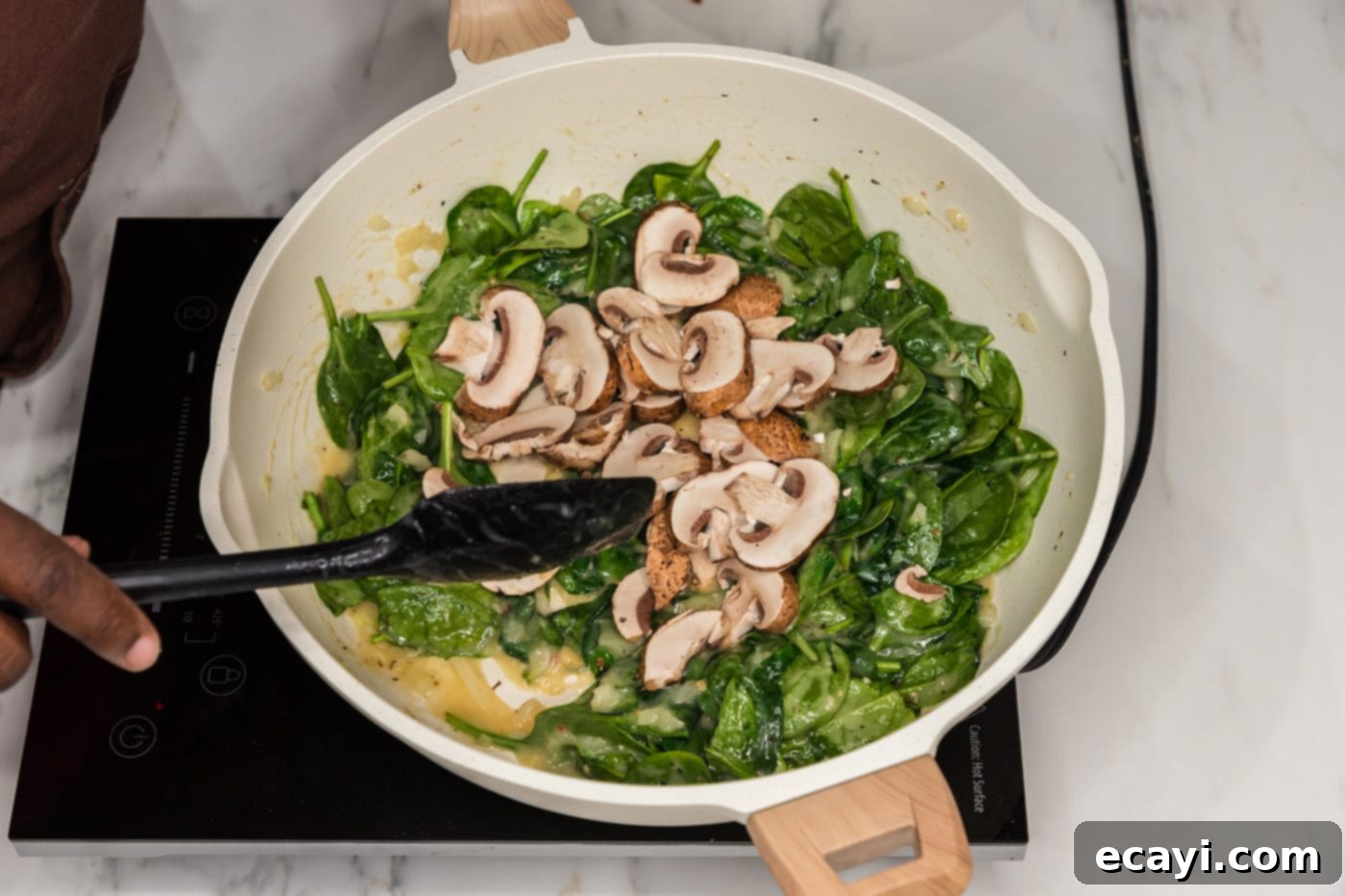 Vibrant Spinach Fettuccine 10 Sliced mushrooms added on top of wilted spinach and sauce in a skillet, ready for the pasta